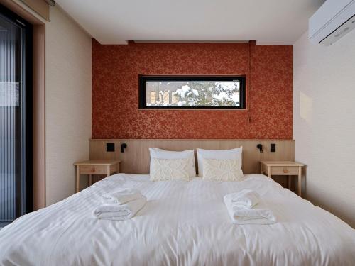 a bedroom with a bed with two slippers on it at Villa Matsu by H2 Life in Nakafurano