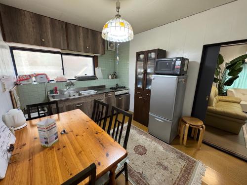 a kitchen with a wooden table and a refrigerator at Rooftop Camping Nagasaki-遊べるホステル-Seven-eleven3min in Nagasaki