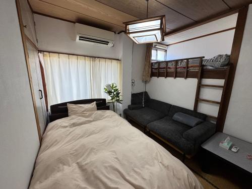 a bedroom with a bed and a bunk bed and a couch at Rooftop Camping Nagasaki-遊べるホステル-Seven-eleven3min in Nagasaki