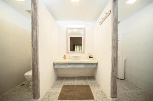a bathroom with a sink and a toilet and a mirror at Trikora Beach Club and Resort in Telukbakau