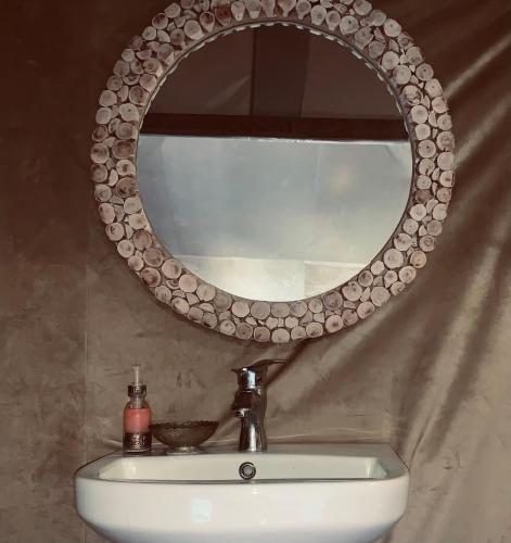 a bathroom sink with a circular mirror above it at Azadic luxury tents in Merzouga