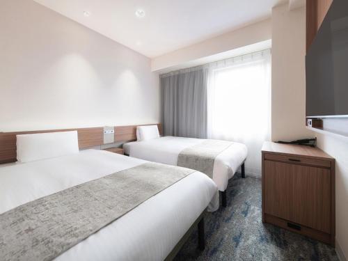 a hotel room with two beds and a television at Vessel Inn Hakata Nakasu in Fukuoka