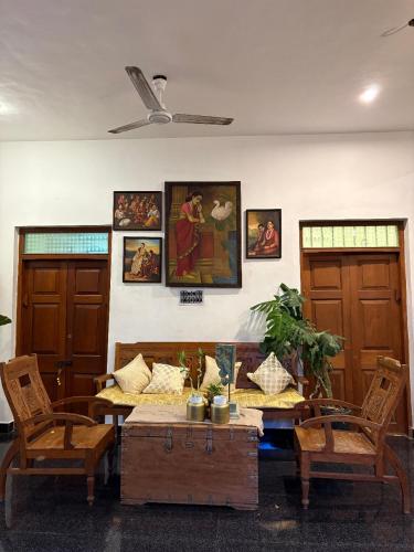 a living room with a table and chairs and paintings at Yaazhi Boutique Homestay in Pondicherry