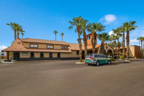 a car parked in front of a house with palm trees at Quality Inn & Suites Goodyear - Phoenix West in Goodyear