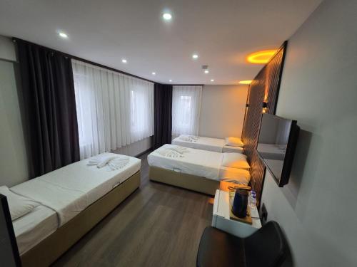 a hotel room with two beds and a flat screen tv at Gizem Pansiyon in Çanakkale