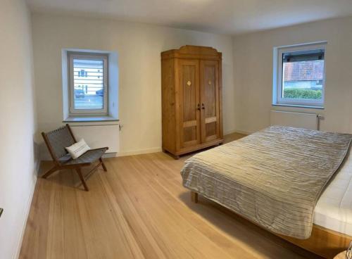 a bedroom with a bed and a chair and two windows at Auszeit im Hegau Bodenseenahe Ferienwohnung in Engen
