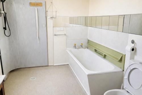 a bathroom with a bath tub and a toilet at Nothing Fancy 90s Queen Room in Whanganui