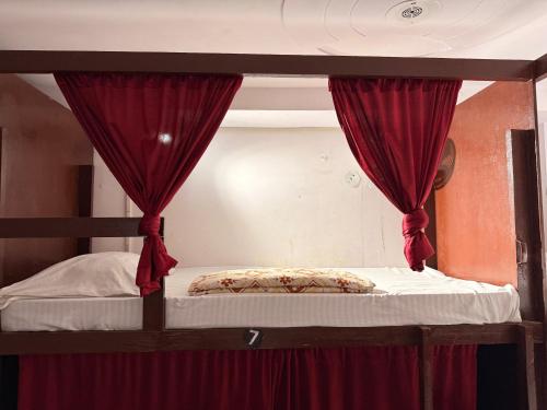 a bunk bed with red curtains and a canopy at Cozy Inn Hostel in New Delhi