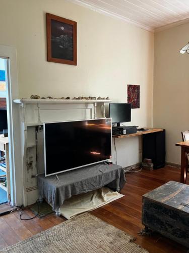 a living room with a flat screen tv on a shelf at Nothing Fancy 90s Queen Room in Whanganui