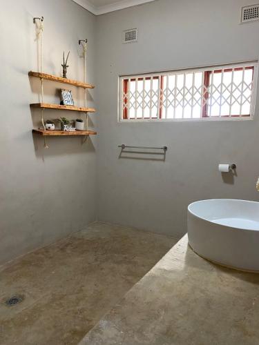 a bathroom with a white tub and a window at Mon Desir Estate - BR4 in Pietermaritzburg