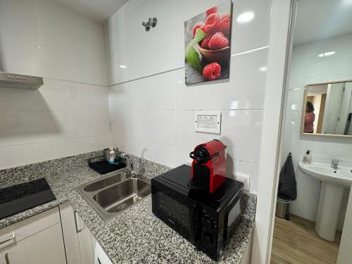 a kitchen with a sink and a red machine on a counter at Apartamentos San Nicolás AIRE AC y ascensor junto a Laurel in Logroño