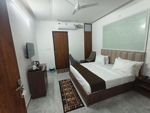 a bedroom with a bed and a chair and a tv at Hotel Yashoday in Kekri