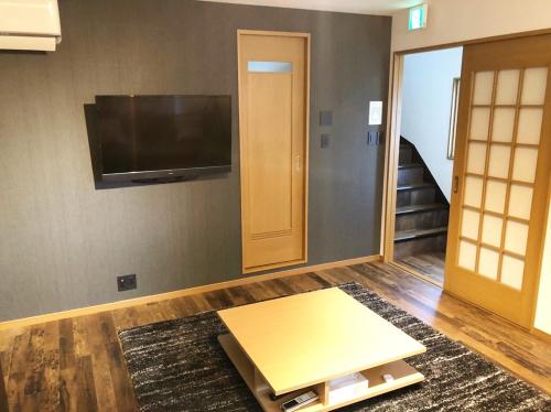 a living room with a flat screen tv on a wall at Chill Inn Honan by Tranova in Tokyo