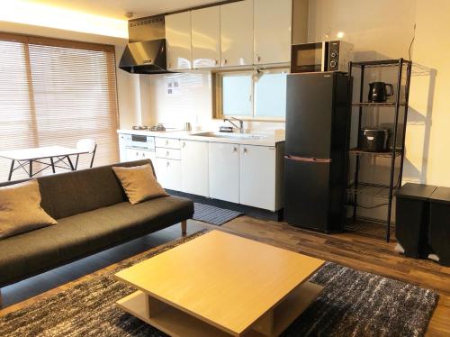 a living room with a couch and a kitchen at Chill Inn Honan by Tranova in Tokyo