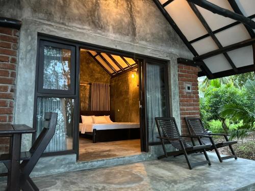 a patio with two chairs and a bed in a room at Aji fruit farm cottage peaceful lakeside farm stay with sunrise views 01 in Embilipitiya