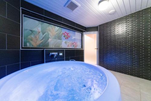 a large tub in a bathroom with a painting on the wall at HOTEL ARIA-Yokohama Kannai in Yokohama