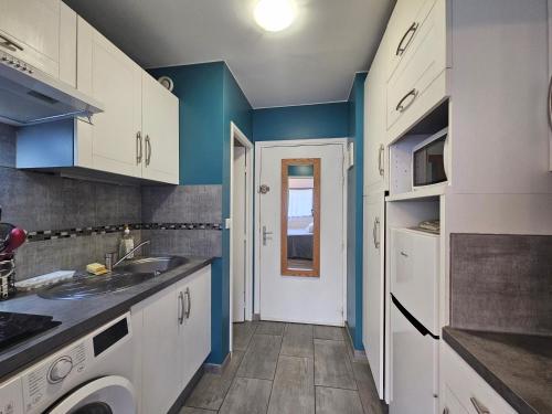 a kitchen with white cabinets and blue walls at Studio 2 étoiles proche thermes avec parking in Aix-les-Bains