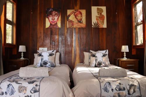 two beds in a room with pictures on the wall at Mukuku Oasis Lodge in Shimweghe