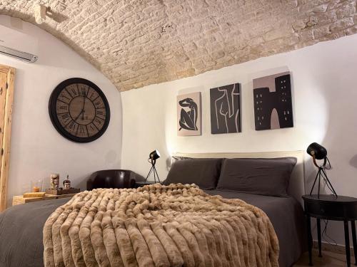 a bedroom with a bed and a clock on the wall at Himeros Trulli Area in Alberobello