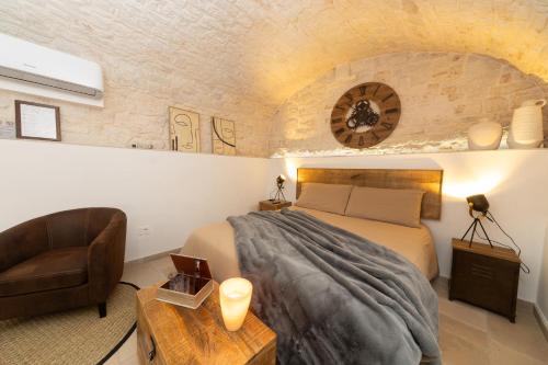a bedroom with a bed and a couch and a chair at Himeros Trulli Area in Alberobello
