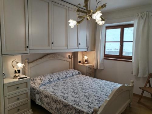 a bedroom with a bed with white cabinets and a chandelier at Casa vacanze tortoi in Candide