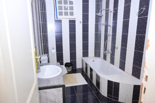 a black and white bathroom with a tub and a sink at Qasr El Nil in Luxor
