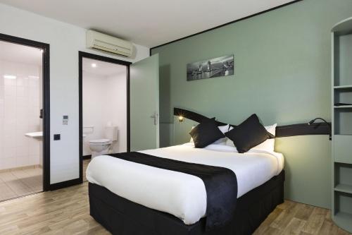 a bedroom with a large bed and a bathroom at Enzo Hotels Chartres Mainvilliers in Chartres