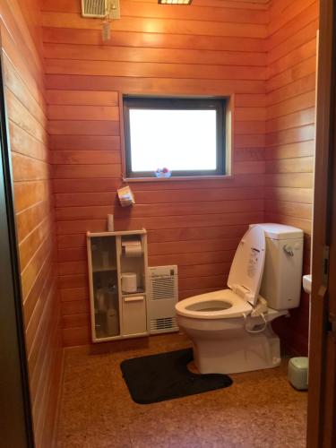 a bathroom with a toilet in a wooden wall at つむぐ家2 in Ueda