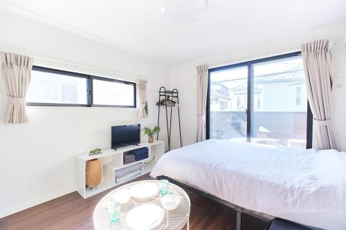 a white bedroom with a bed and a window at Base Hanegi Apartment by Tranova in Tokyo