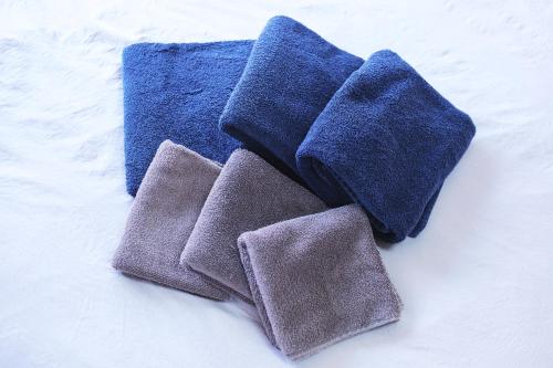 a group of four towels sitting on a bed at Base Hanegi Apartment by Tranova in Tokyo