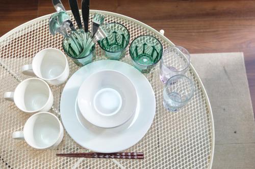 a table with plates and cups on a table at Base Hanegi Apartment by Tranova in Tokyo
