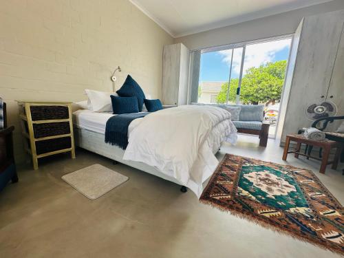 a bedroom with a bed and a large window at WestBed in Langebaan