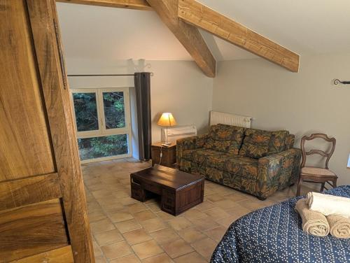 a living room with a couch and a bed and a table at Chambres d'hôtes - Le Mas du Colombeyras in Espeluche