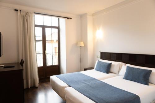 a bedroom with a large bed and a window at Hotel Rincón del Conde in León