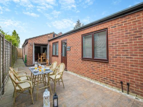 a patio with a table and chairs and a brick wall at The Lodge in Gloucester