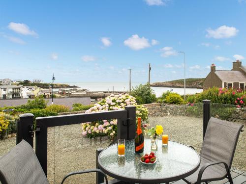 a table with drinks and flowers on a balcony at Harbour View in Cemaes Bay