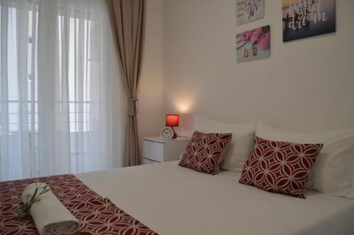 a bedroom with a white bed with red pillows at Yeshill Deluxe Apartment in Budva