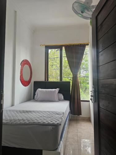 a bedroom with a bed and a window at Ibu ana quest house in Tabanan