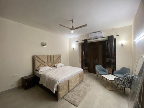 a bedroom with a bed and two chairs in it at Mitron Farms in New Delhi