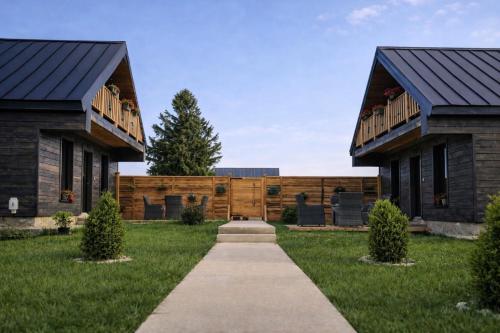 two houses in a yard with a sidewalk at Adria Nord Chalets in Žabljak