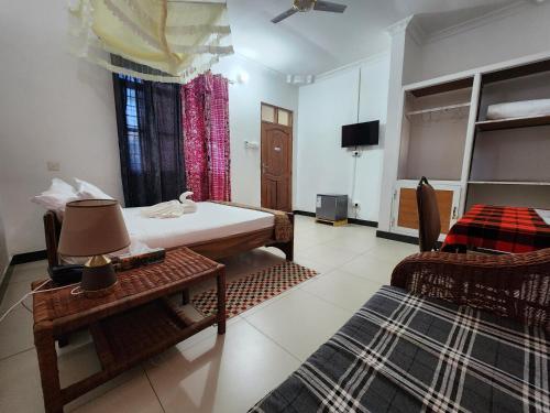 a bedroom with a bed and a table and a tv at MaTemu Square in Mapinga
