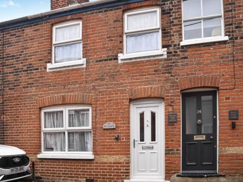 a brick house with a white door and windows at Maydrift in Mundesley
