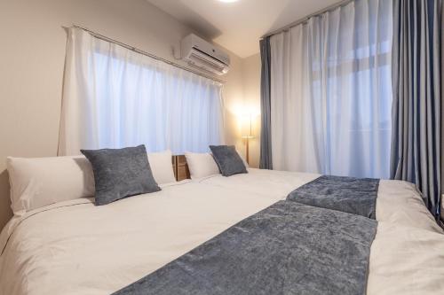 a bedroom with a large white bed with blue pillows at Eldor Nishikoujiya Apartment by Tranova in Tokyo
