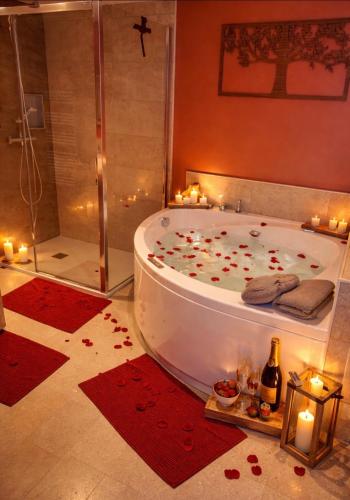 a bathroom with a tub with candles and a shower at Au fil de l’Ô in Bisseuil