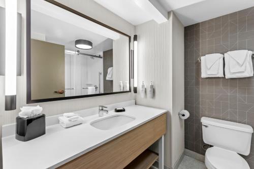 a bathroom with a sink and a toilet and a mirror at Spark by Hilton Bardstown in Bardstown