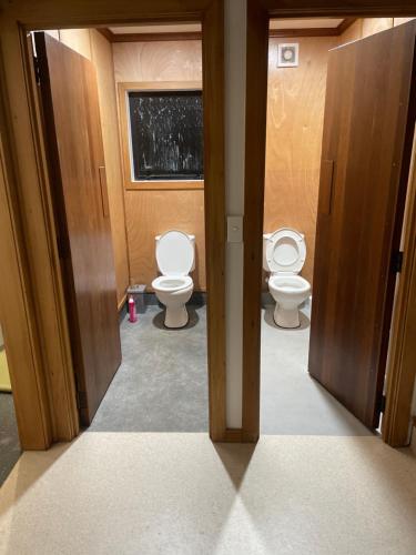 two toilets in a bathroom with two open doors at Leigh Backpackers in Leigh