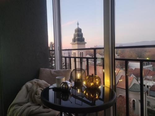 a table in front of a window with a view of a church at Apartman Riva Panoramska terasa & Privatna Garaža in Kraljevo