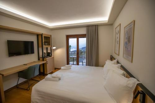 a bedroom with a bed with a desk and a television at Agnanti Limnis Hotel in Neochori