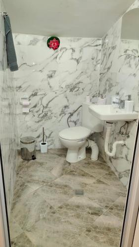 a bathroom with a white toilet and a sink at Къща за гости Балканъ in Kyustendil