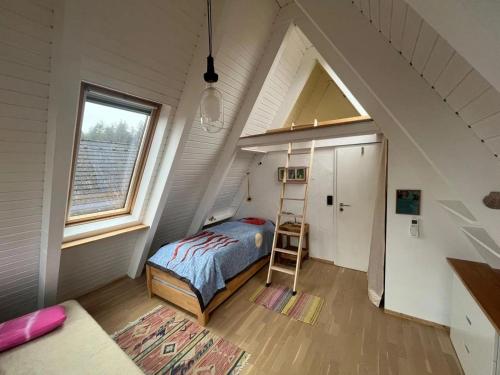 a small attic bedroom with a bed and a ladder at NurdachZeit – Ferienhaus in Schellbronn in Neuhausen